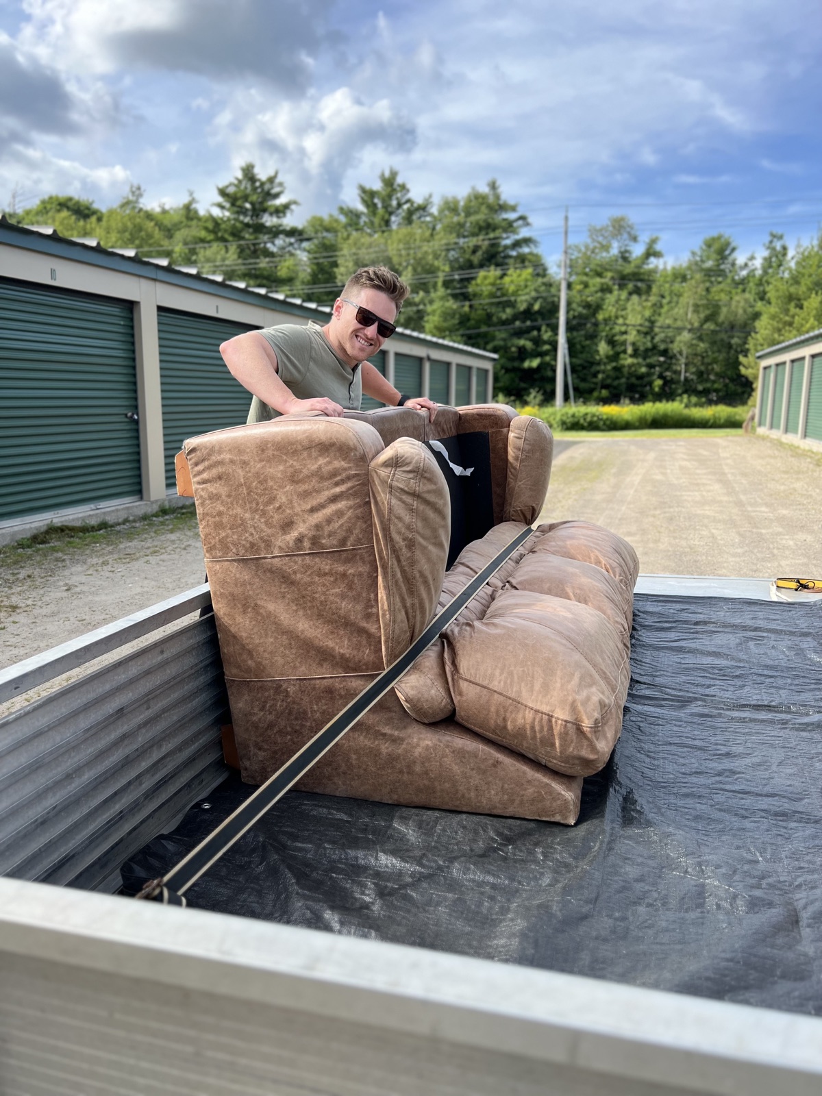 Tim MacLeod strapping a leather couch into his trailer outside a row of storage units